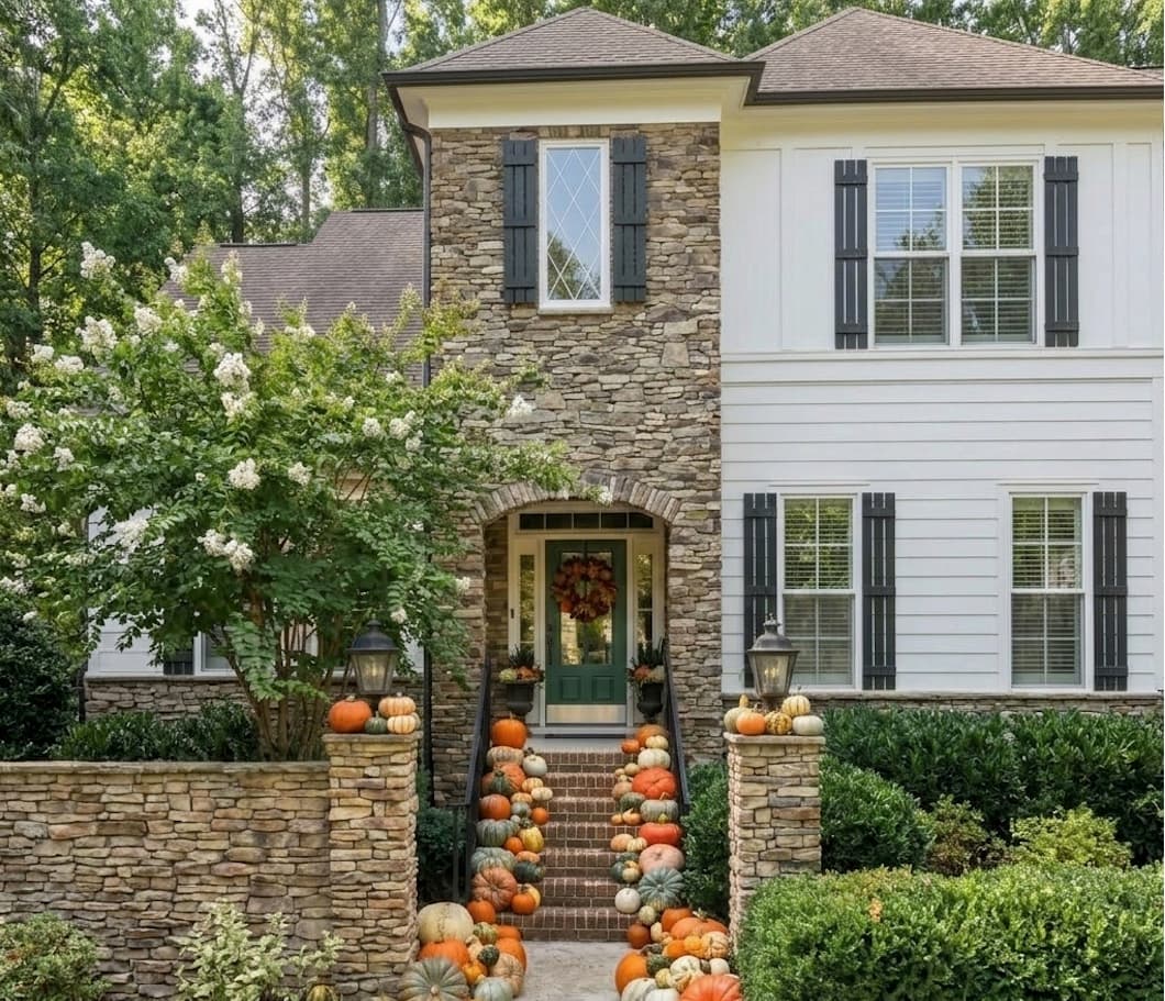 Stone entryway with pumpkin-lined steps leading to a green front door, styled by The Charming Stoop